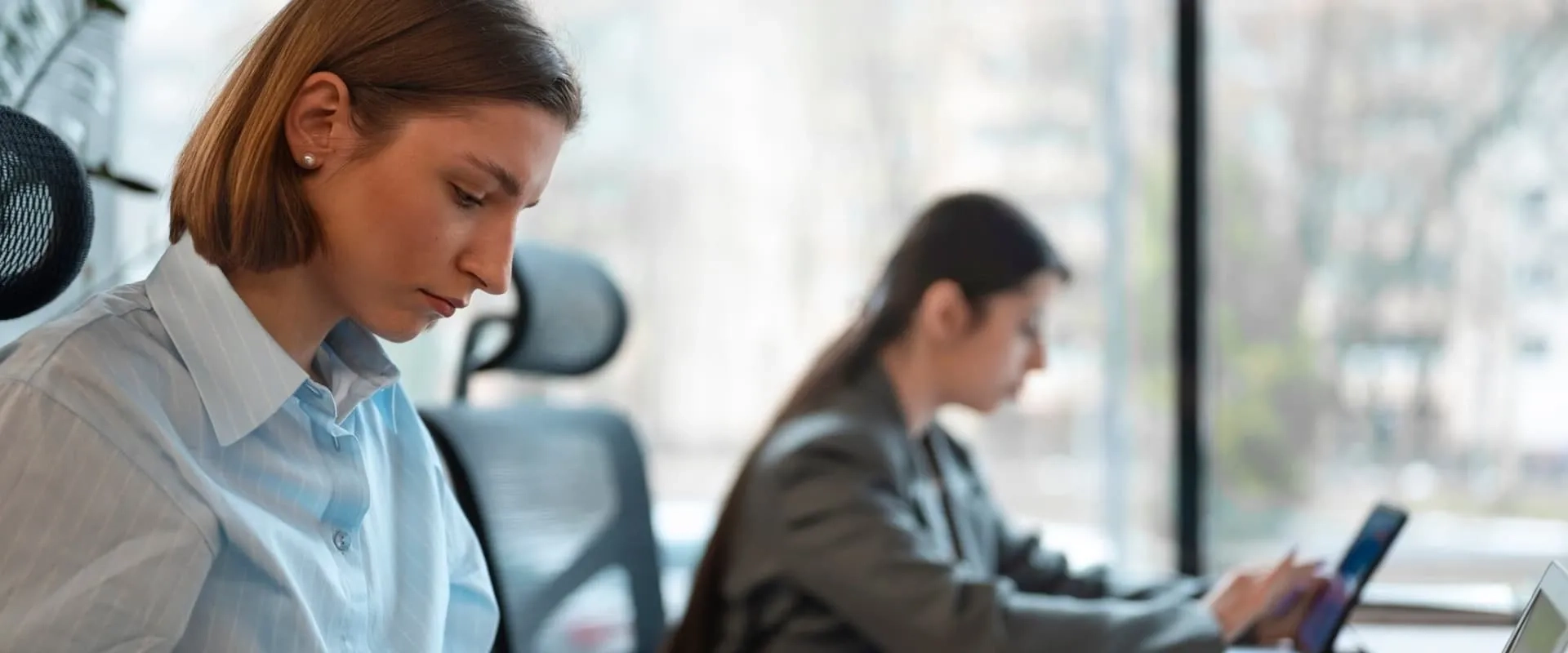 Mujeres profesionales trabajando concentradas en un espacio de coworking moderno, utilizando computadoras portátiles.
