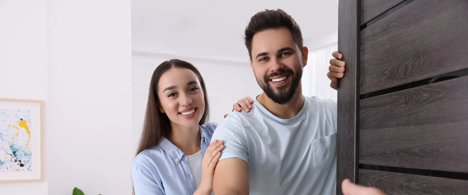Joven sonriente frente a una casa nueva simbolizando la compra de vivienda antes de los 30 años con apoyo de Infonavit.