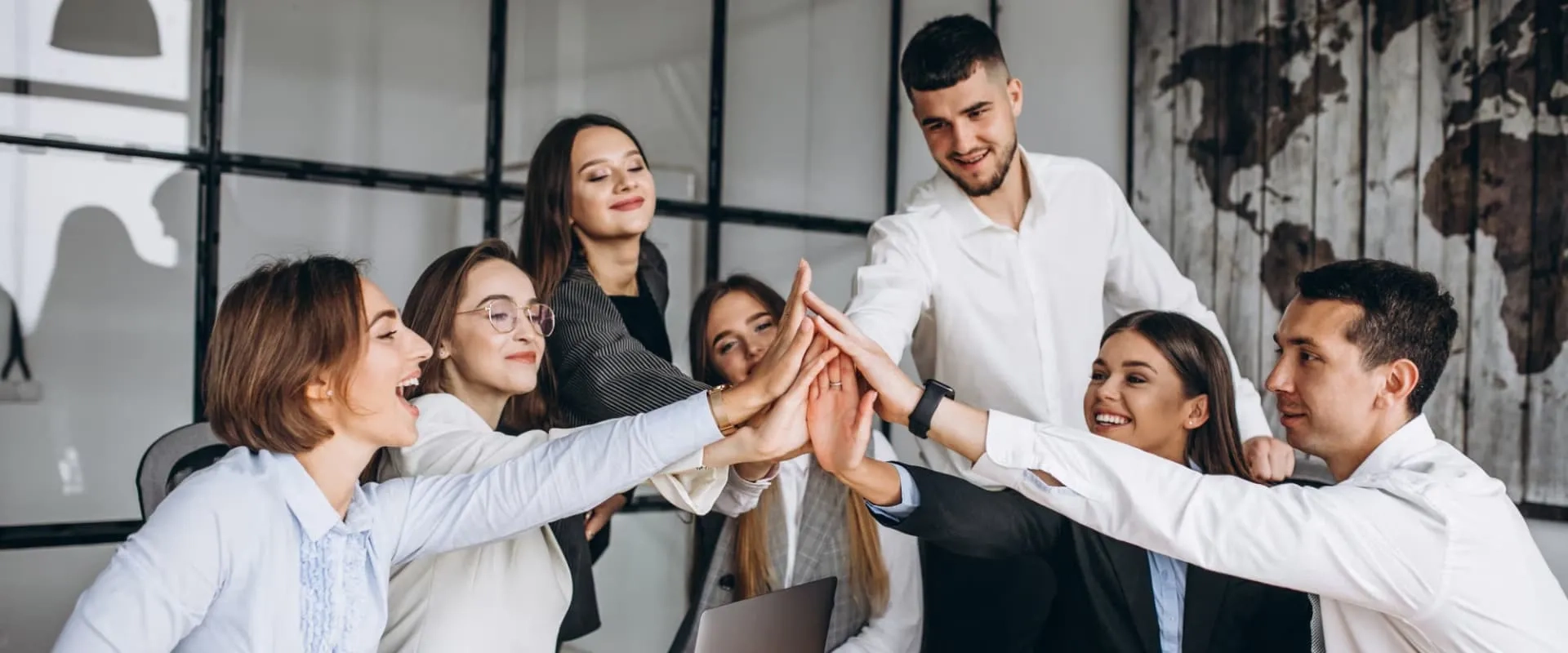 Un grupo de ocho personas en una oficina, celebrando con un gesto de 'high five' en el centro