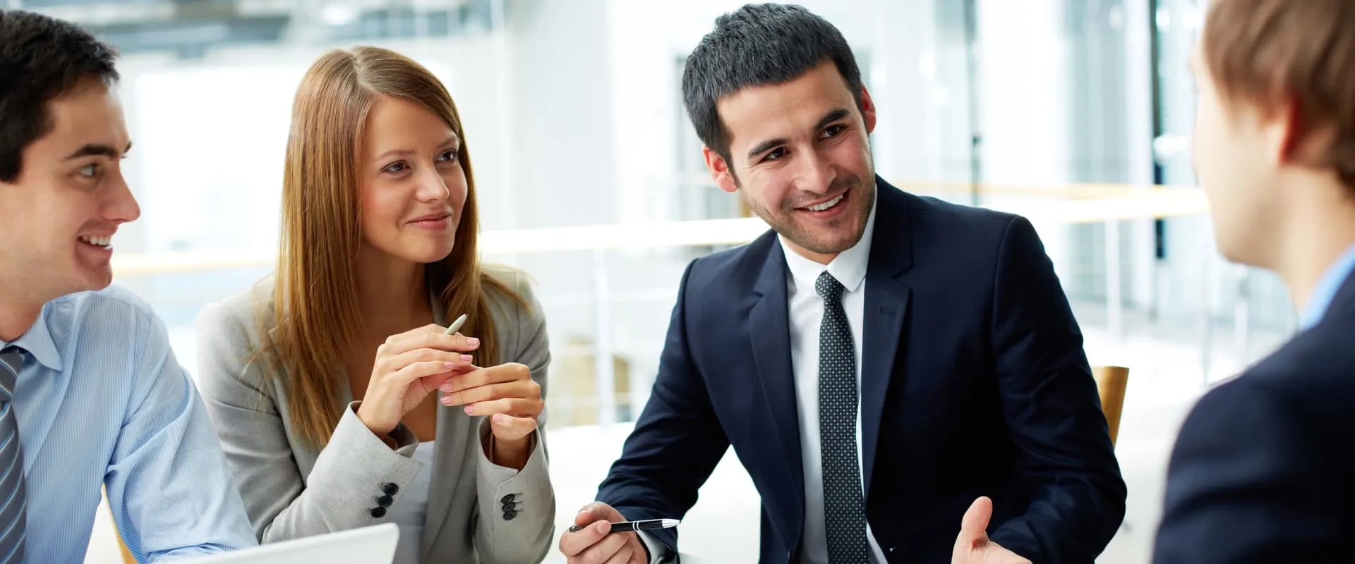 Reunión de trabajo entre jóvenes profesionales en traje de negocios, destacando el trabajo en equipo y la comunicación efectiva en entornos corporativos.